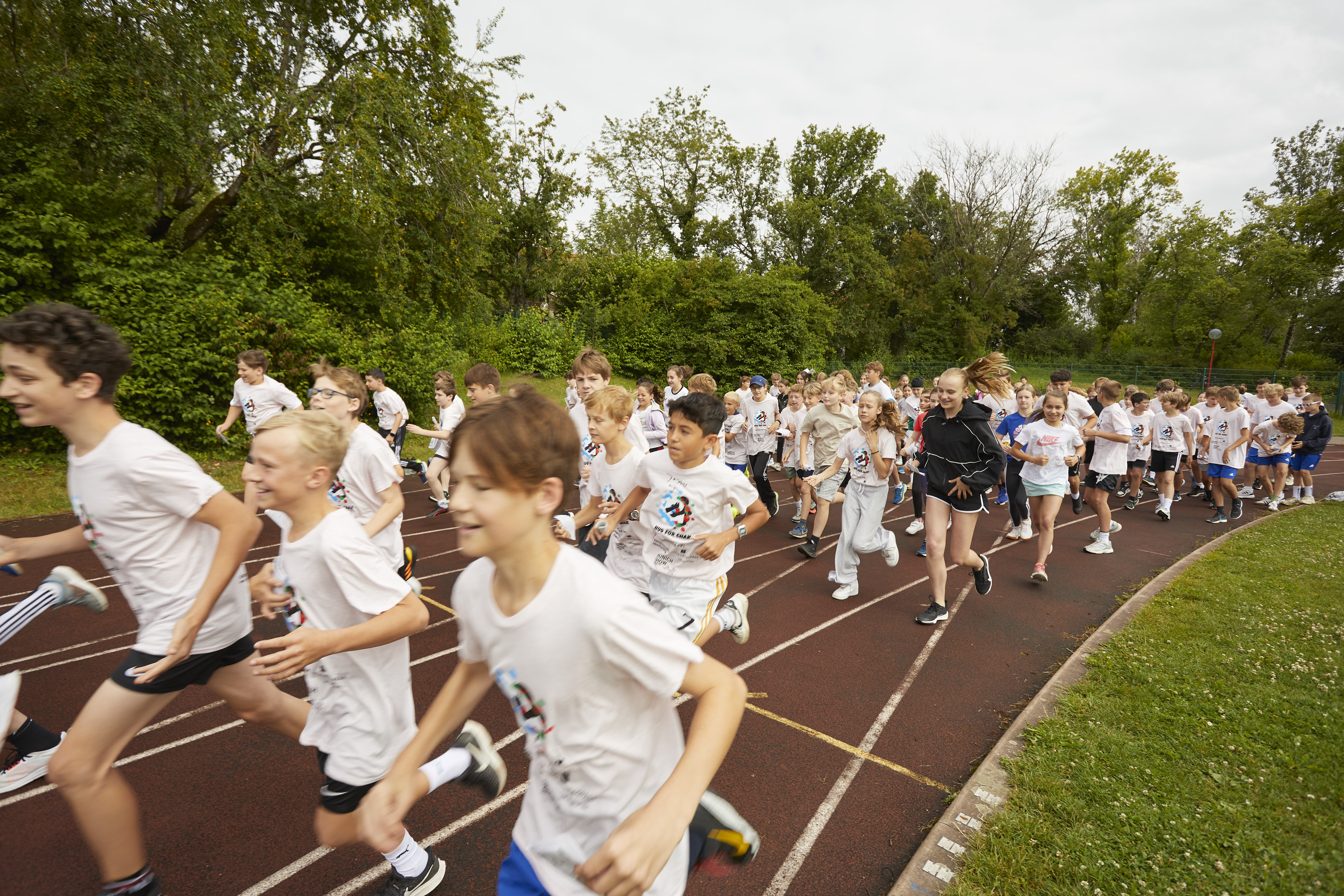 Kinder laufen Runden um den Sportplatz